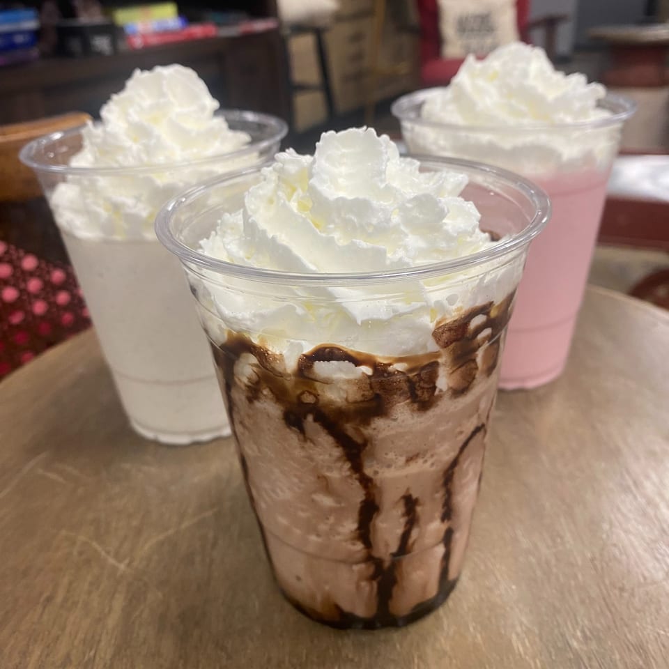 Three Redhouse Bagels Bensalem milkshakes, chocolate, vanilla, and strawberry, topped with whipped cream.