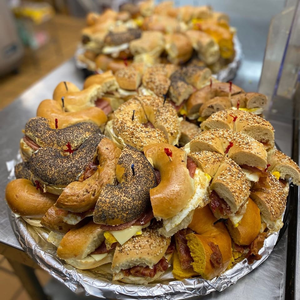 A large catering platter filled with various Redhouse Bagels breakfast sandwiches, some with poppy seeds or sesame seeds.