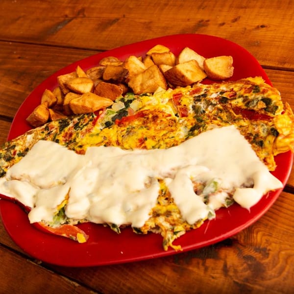 A Redhouse Bagels omelet with melted cheese and home fries on a red plate.